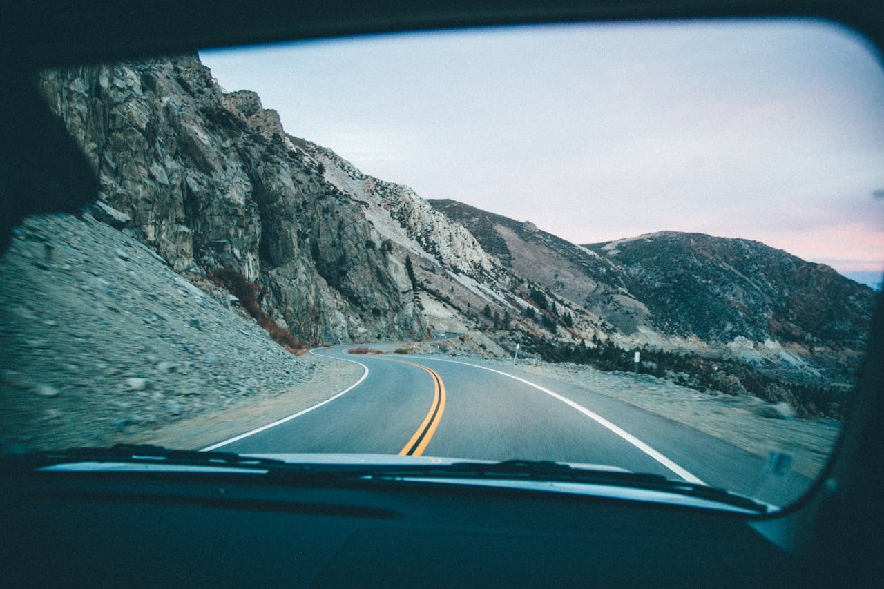 about-me-01 View of a winding mountain road through a car windshield during a road trip.